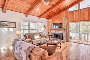 Cozy living area with a high ceiling, comfortable sofa set, and stone fireplace.