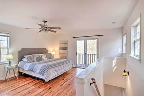 Relax in this serene bedroom with a large bed, nightstand, and lamp, plus a ceiling fan and balcony access.
