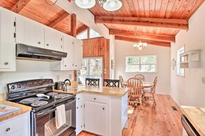 Cozy kitchen with central island, stove, and dining area, featuring a rustic ceiling with exposed beams.