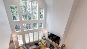 A spacious living room with a large sectional sofa, a fireplace, and multiple windows offering a view of the outdoors.