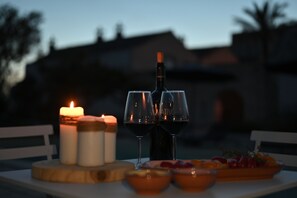 Una mesa dispuesta con una botella de vino, dos copas, una vela y una bandeja de frutas.