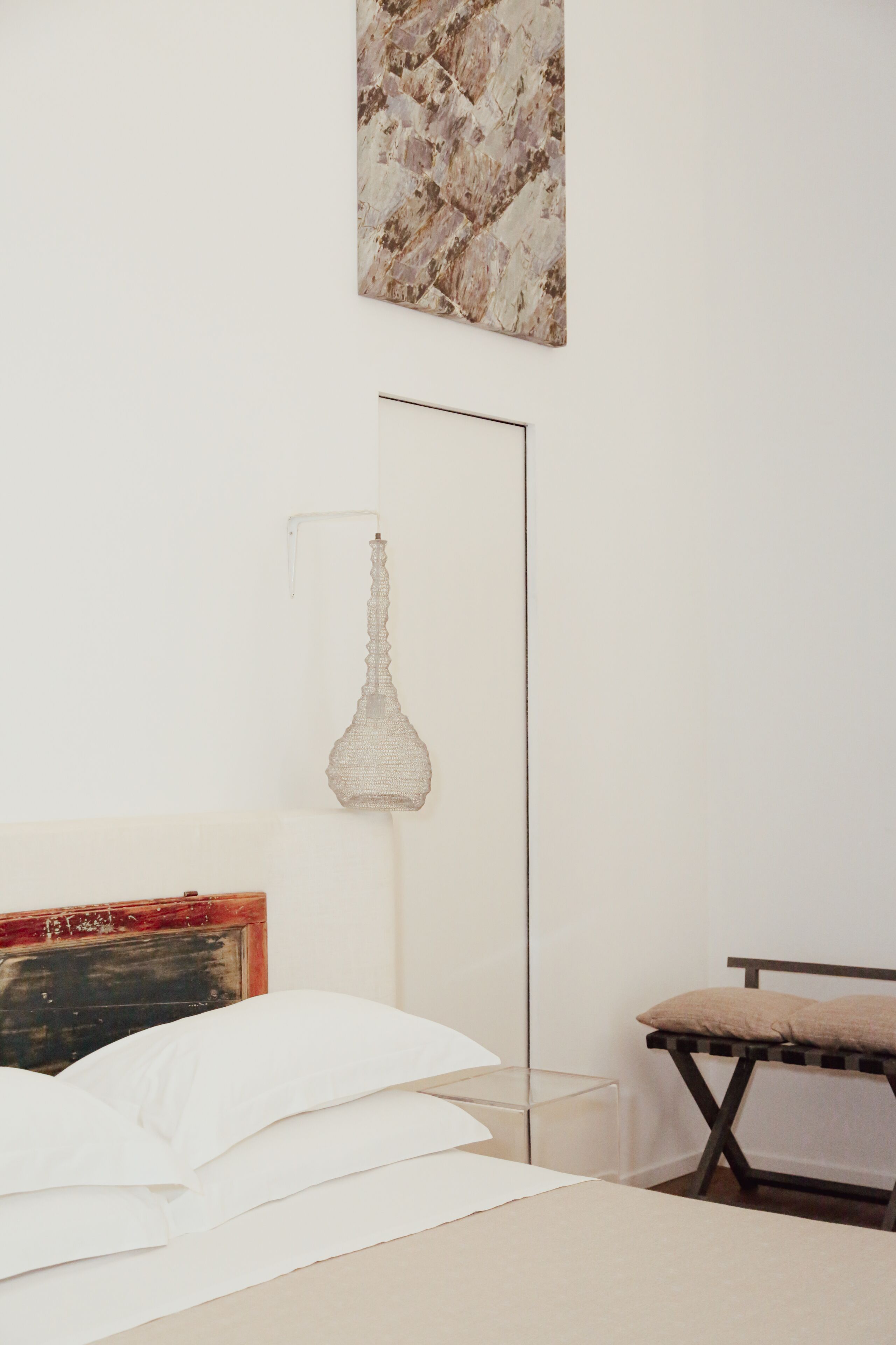 Une chambre à coucher au style minimaliste, avec un lit, une table de chevet et une lampe sur pied.