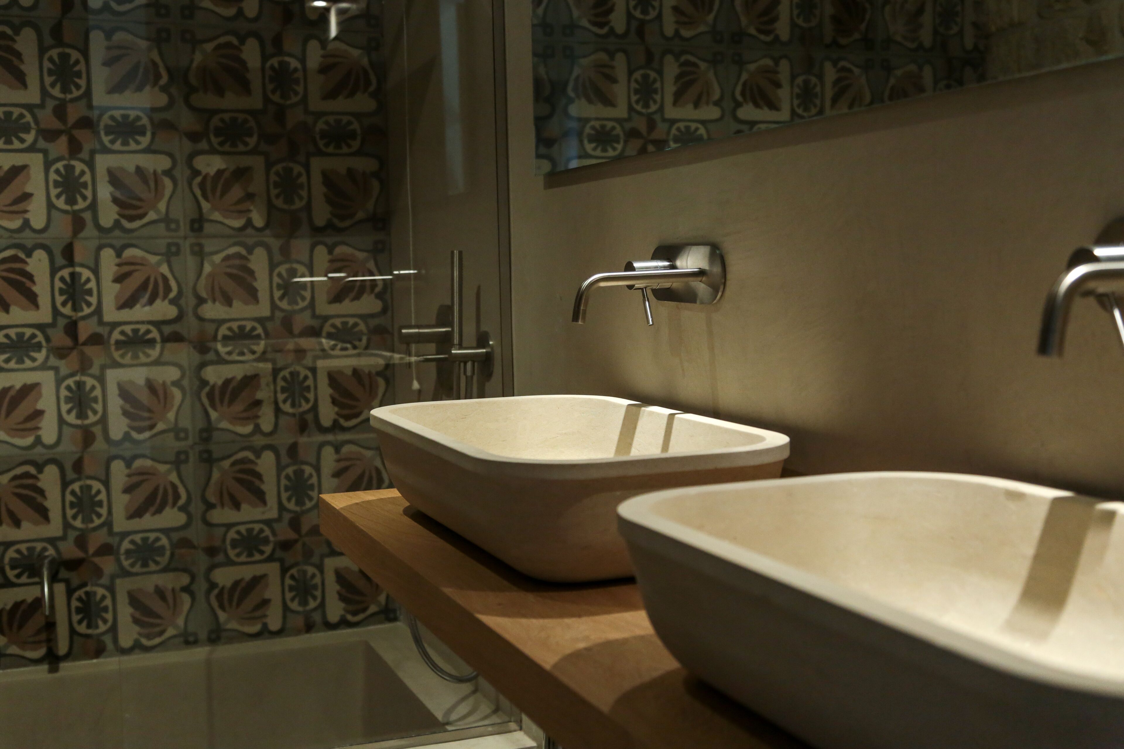A bathroom with two sinks, a shower, and a patterned tile backsplash.