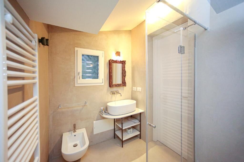 Une salle de bain moderne avec un lavabo blanc, un bidet, un miroir et un porte-serviettes.