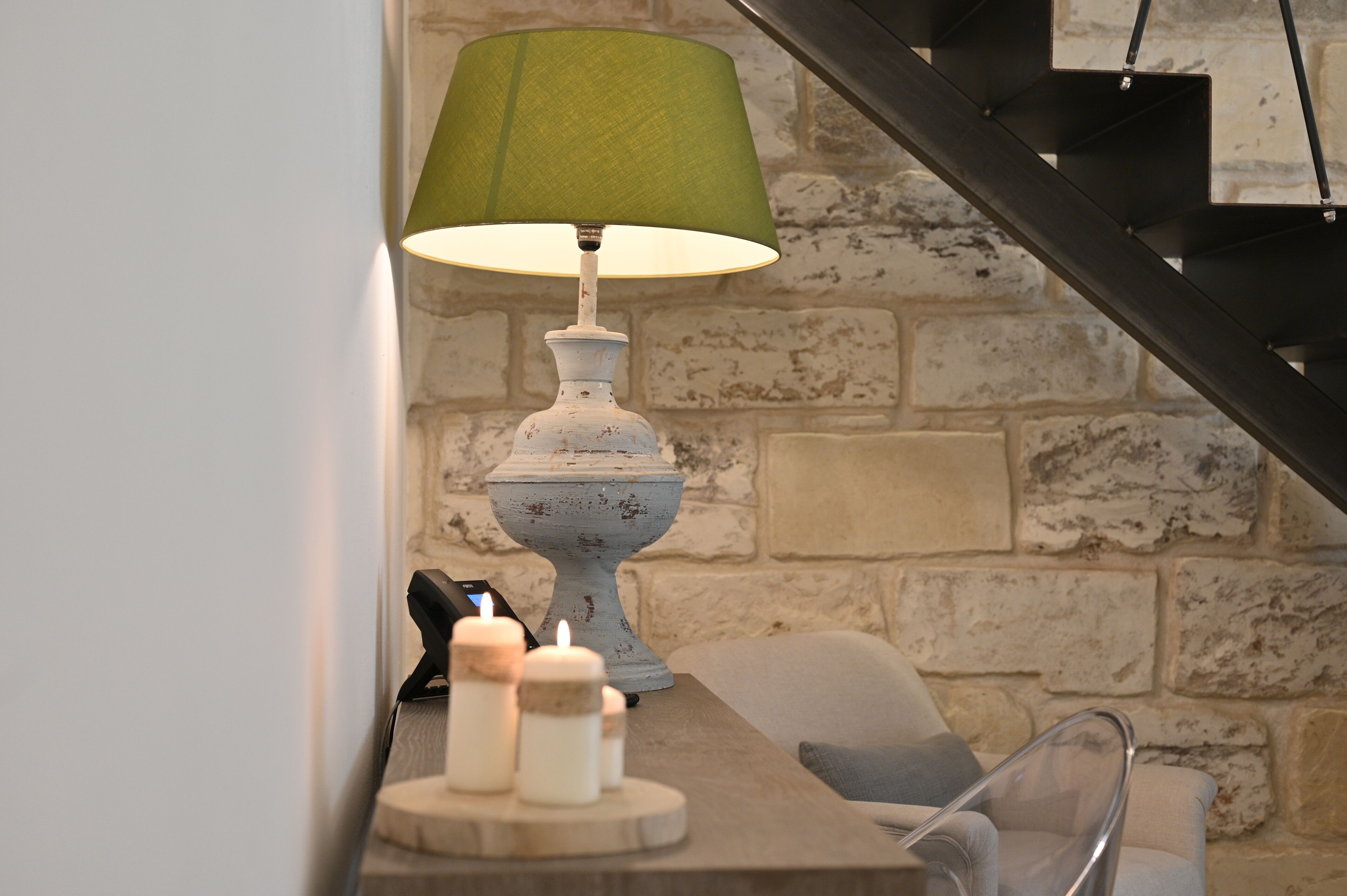 A table with a green lamp, candles, and a vintage-style lamp base.