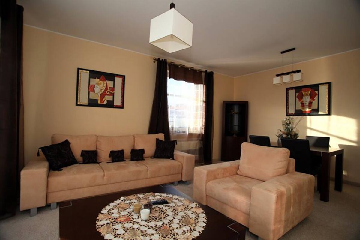 A living room with a beige sofa, a matching armchair, a coffee table, and artwork on the walls.