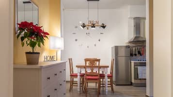 Una cucina moderna con zona pranzo, che include un tavolo in legno con sedie, un frigorifero e un fornello.