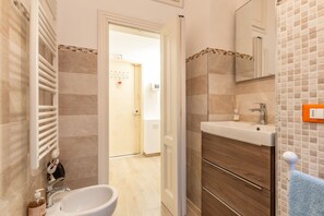 Een moderne badkamer met een wit wastafelmeubel, een spiegel en een houten ladeblok.