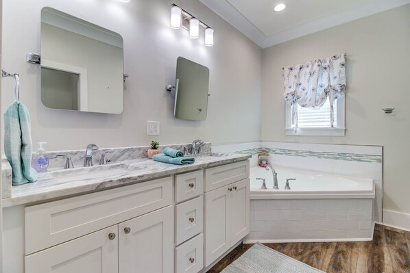 Une salle de bain moderne avec deux lavabos, un grand miroir et une baignoire.