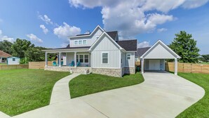 A two-story house with a covered porch, a garage, and a well-maintained lawn. - Bright beach house steps from the sand & memories (Long Beach)