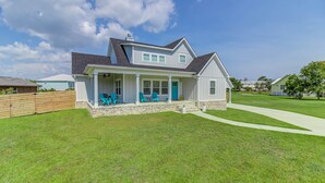 A two-story house with a covered porch, a stone foundation, and a well-maintained lawn. - Bright beach house steps from the sand & memories (Long Beach)