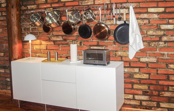 A kitchen with a brick wall background, a white countertop, and various kitchen utensils and appliances.