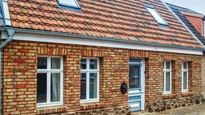 Een traditioneel bakstenen gebouw met een pannendak, meerdere ramen en een stenen fundering.
