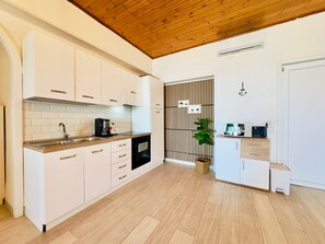 A modern kitchen with white cabinets, a wooden ceiling, and a built-in oven.