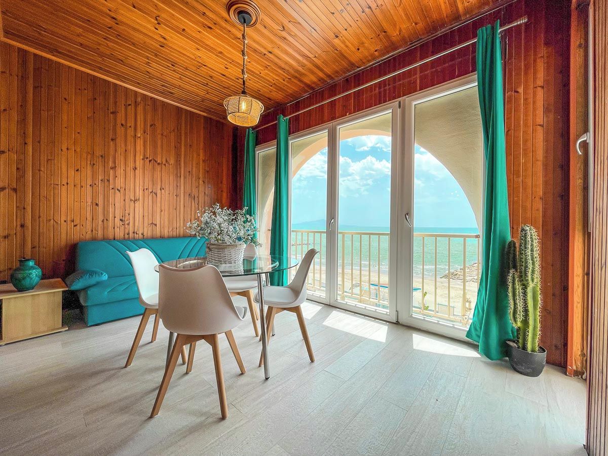 Un interno in legno con zona pranzo, divano e vista sulla spiaggia.