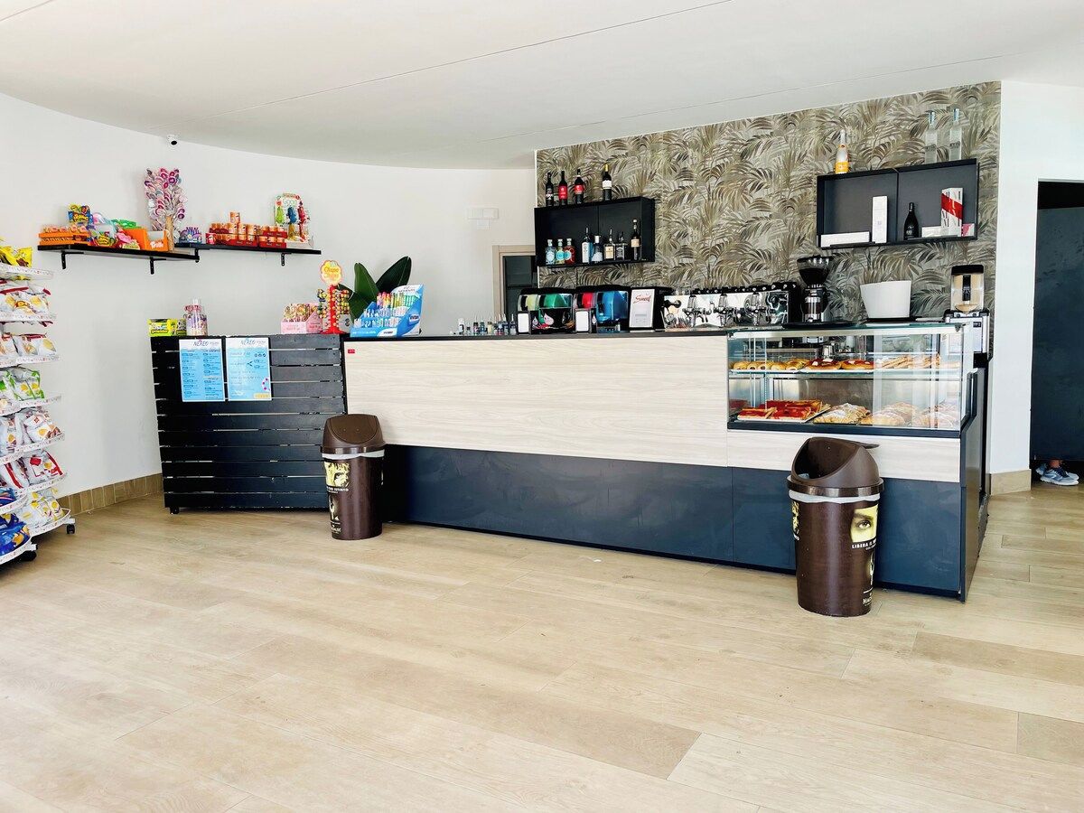 A clean, modern reception area with a counter, shelves with various items, and trash bins.