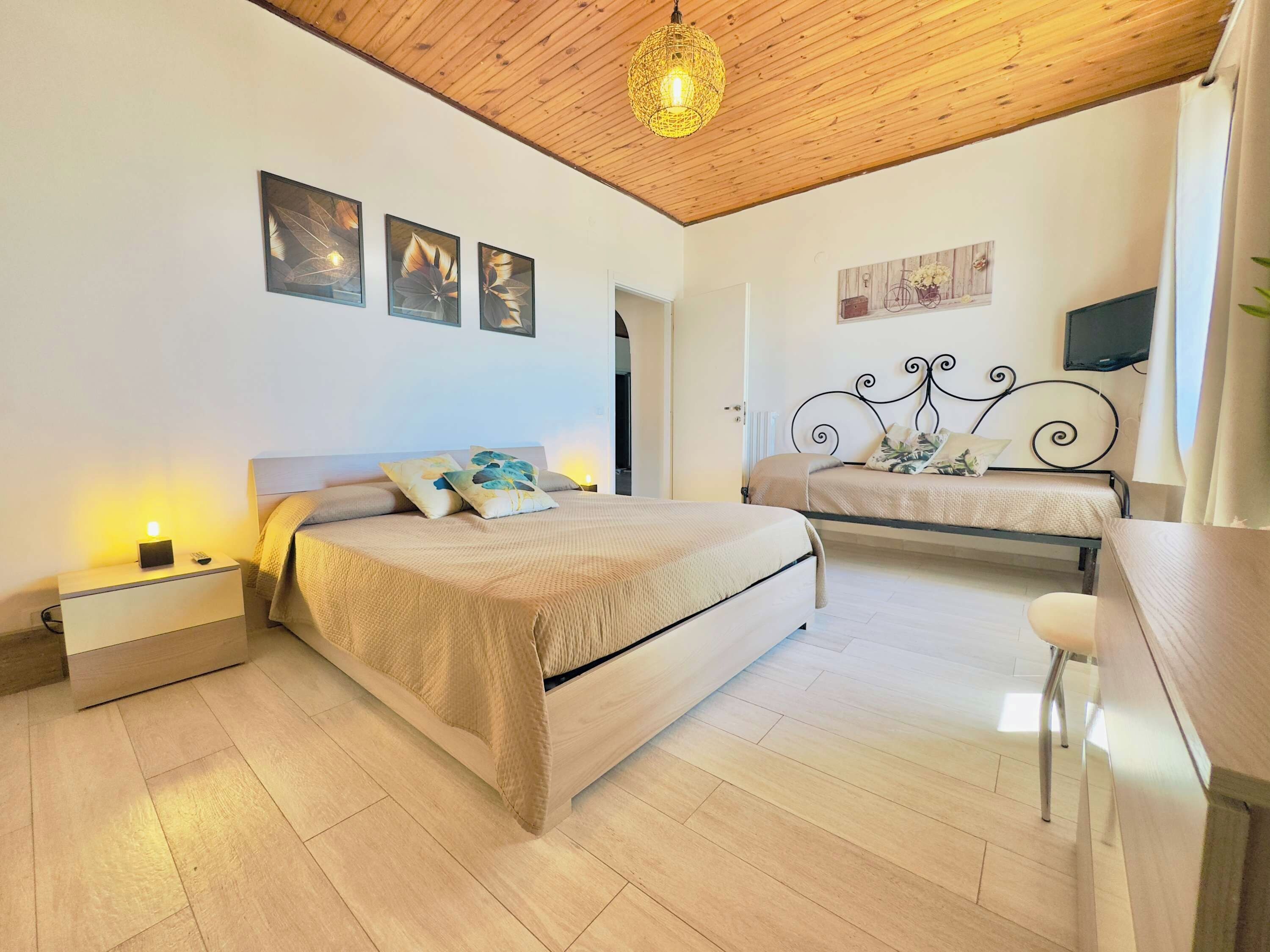Une chambre avec deux lits, un plafond en bois et un téléviseur fixé au mur.