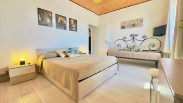 Une chambre avec deux lits, un plafond en bois et un téléviseur fixé au mur.