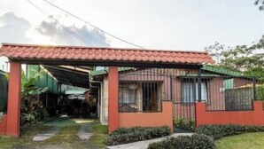 A house with a red roof, a covered porch, and a gated entrance. - Tikita family house in La Fortuna downtown (La Fortuna)