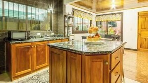 A kitchen with wooden cabinets, a granite countertop, and a built-in microwave. - Tikita family house in La Fortuna downtown (La Fortuna)