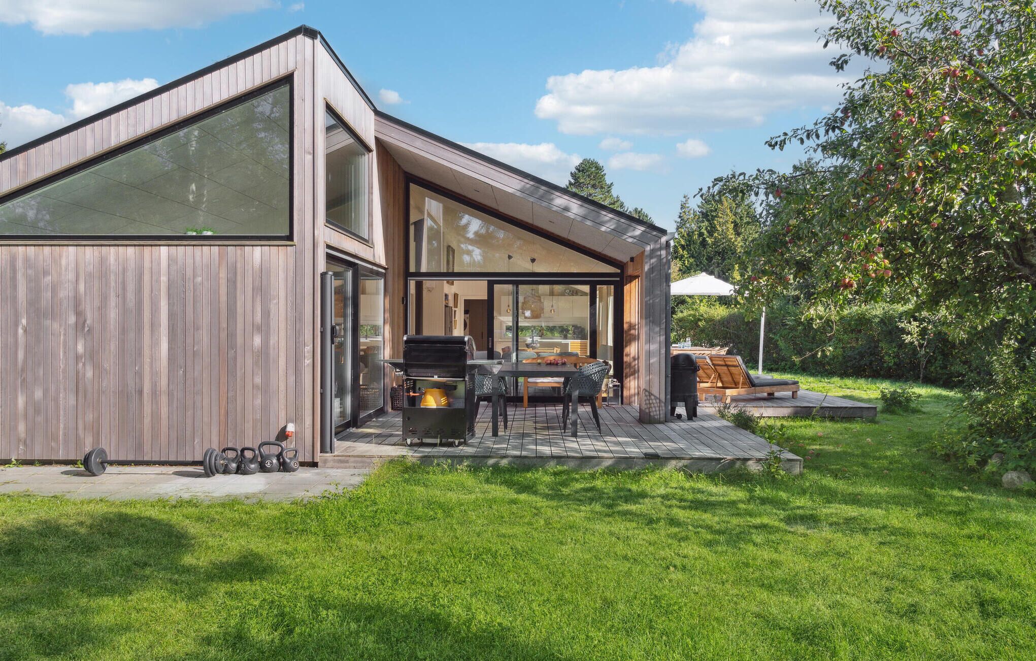 A modern house with a large glass door, a barbecue area, and a deck.