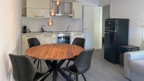 Eine moderne Küche mit einem runden Holztisch, schwarzen Stühlen und Pendelleuchten.