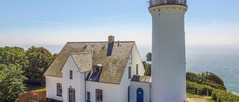 Stunning lighthouse with a keeper's residence or storage building, offering a panoramic view of the sea.