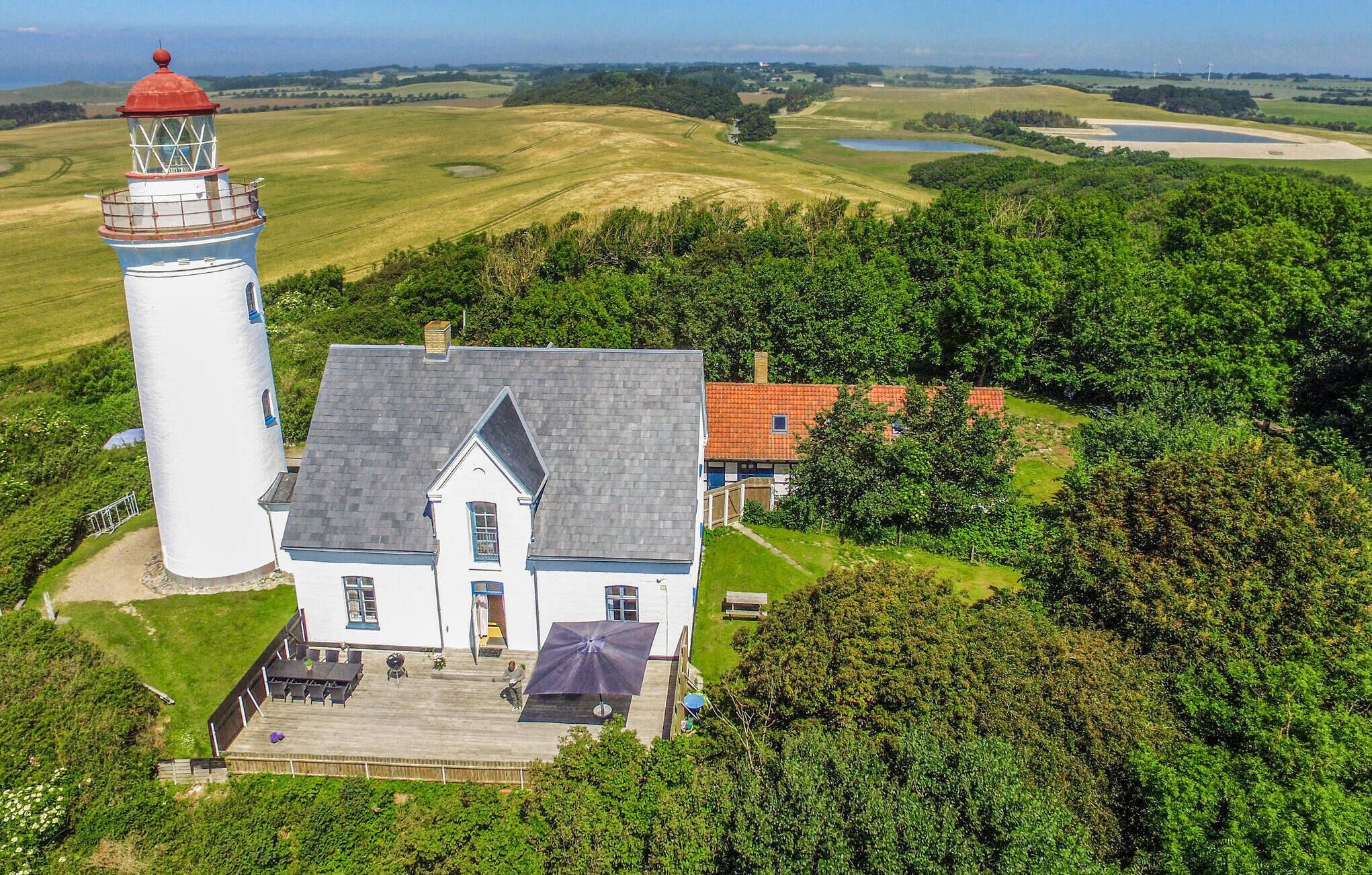Un phare et une maison avec une allée pavée et un espace extérieur aménagé pour s’asseoir.