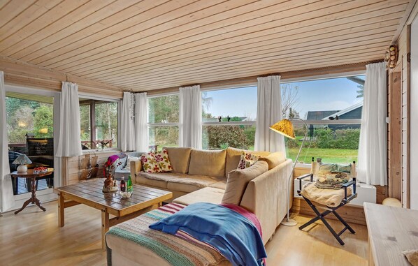 A cozy living room with a sofa, coffee table, and a view of the garden.