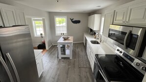 Una cucina moderna con mobili bianchi, un frigorifero in acciaio inox, un forno a microonde e un forno.