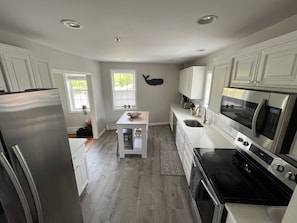 A modern kitchen with white cabinetry, a stainless steel refrigerator, a microwave, and an oven.
