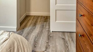 Une pièce avec une commode en bois, une armoire blanche dotée d’une tringle, et un plancher en bois.