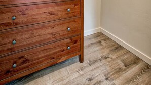 A corner room with a wooden dresser, a ceiling track, and a wooden floor. - The Starlight Retreat | Clean. Bright. Modern. (Redding)