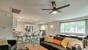 A modern living room with a leather sofa, a wooden coffee table, and a dining area with bar stools.