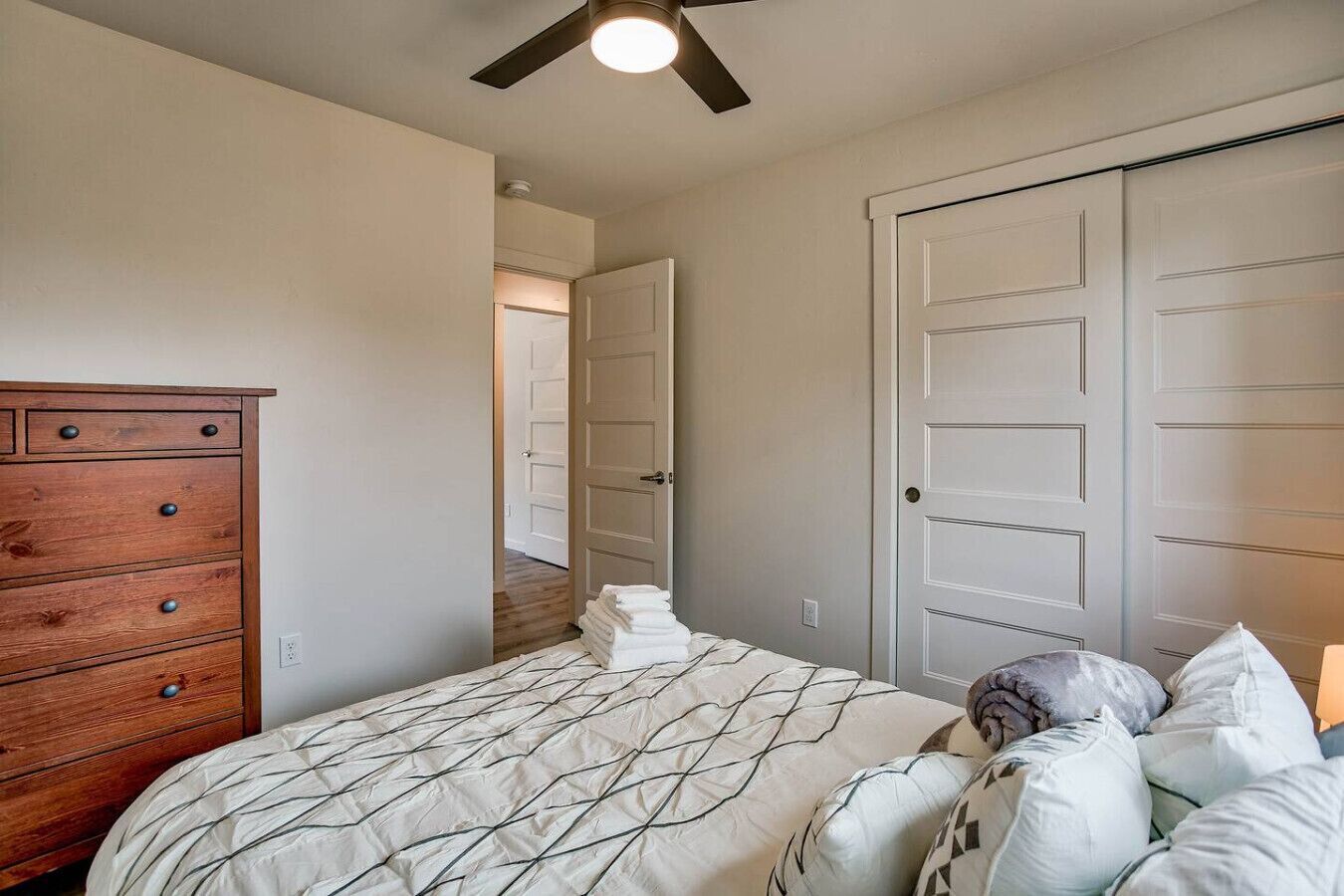 A bedroom with a bed, a wooden dresser, and a closet.