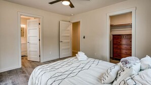 A bedroom with a bed, a ceiling fan, and a walk-in closet.