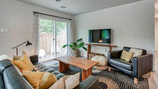 A living room with a sofa, coffee table, TV, and a ceiling fan.