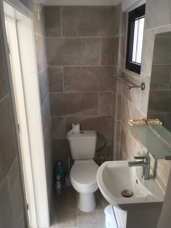 A small bathroom with a toilet, sink, and a window above the sink.