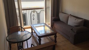 A balcony with a glass table and a sofa, wooden flooring, and a view of the sea. - Charming 1-bed Apartment in Larnaca (Larnaca)