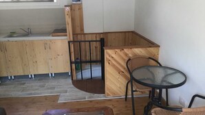 A wooden interior with a kitchen area, a dining table with chairs, and a small seating area. - Charming 1-bed Apartment in Larnaca (Larnaca)