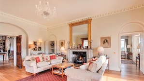 A spacious living room with a fireplace, two sofas, a coffee table, and a large mirror. - Cornish Castle - Luxury Cottages (Saltash)
