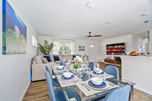 A modern living room with a dining area, a sofa, and a TV displaying 'NETFLIX'.