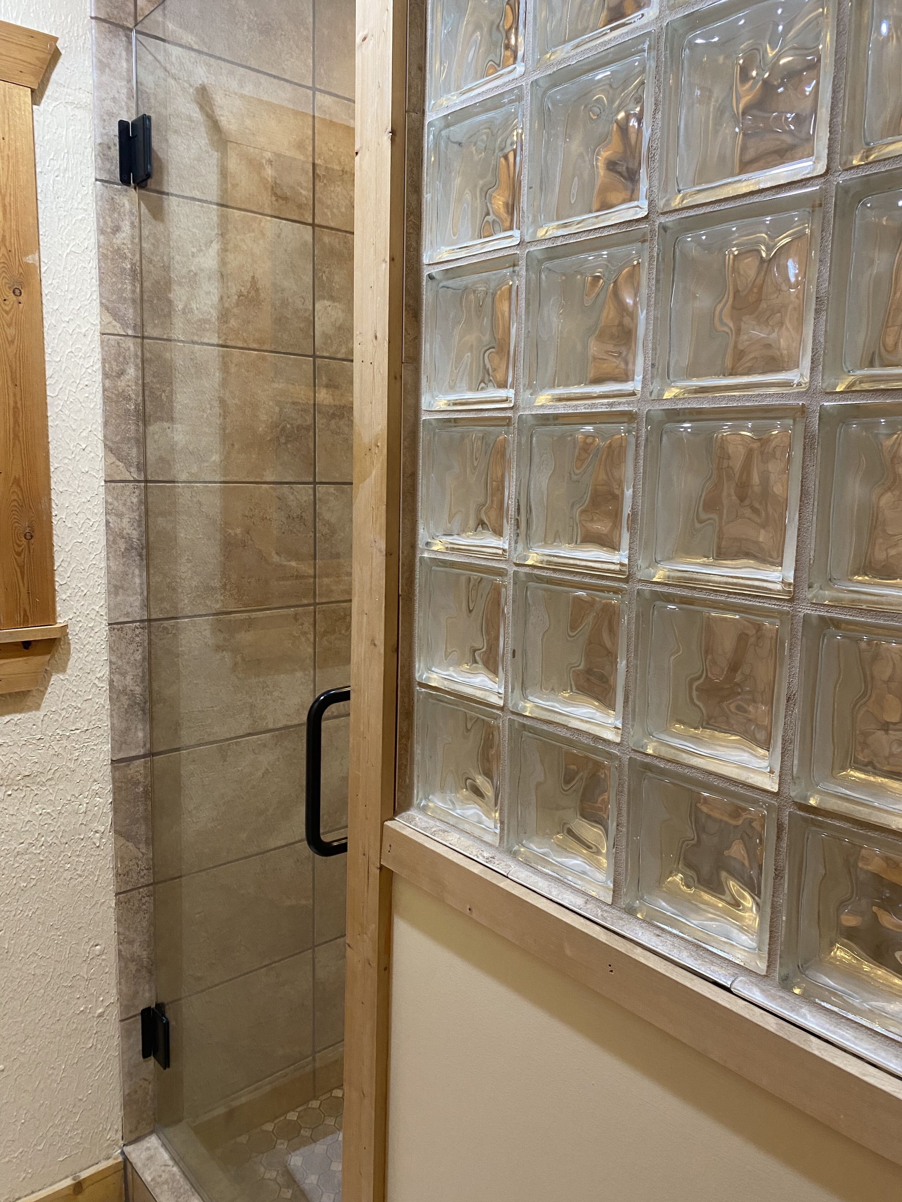 Zona de ducha con paredes de azulejos y ventana de bloques de vidrio.