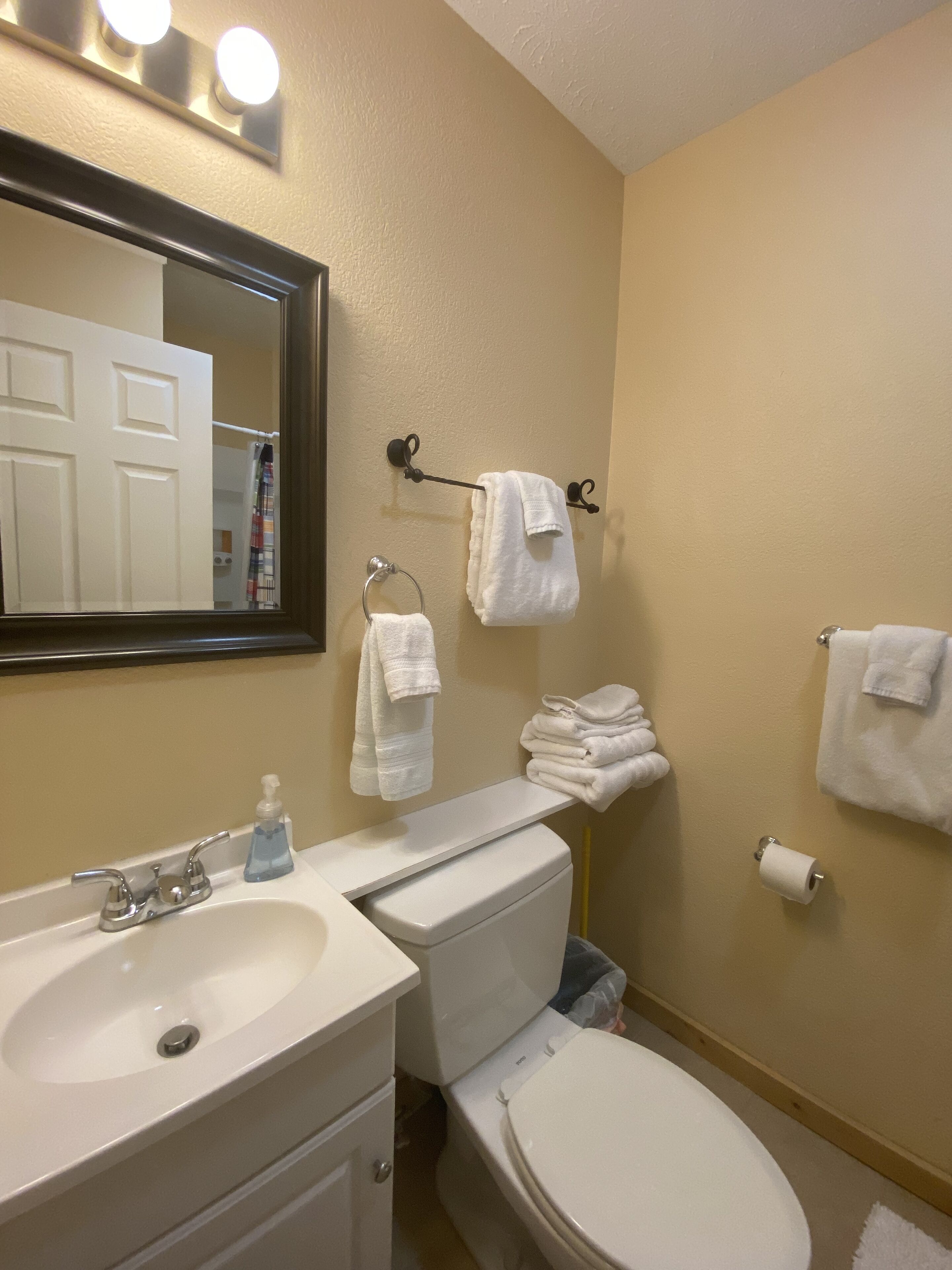 Une salle de bain équipée d’un lavabo, d’un miroir, de toilettes et d’un porte-serviettes.