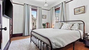 Une chambre à coucher avec un lit, une fenêtre, une porte et un tableau au mur.