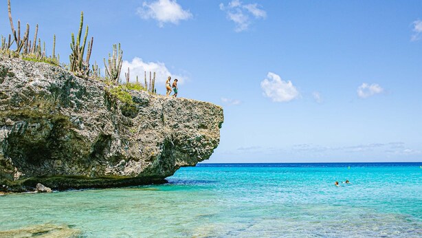 A rocky coastline with clear turquoise water and a small group of people on the cliff. - NEWLY RENOVATED Ocean Front 2 bedroom/ 2 bath, pristine water, divers paradise. (Kralendijk)