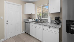 A kitchen with white cabinets, a dishwasher, a sink, a coffee maker, and a refrigerator. - Cozy 2B/1Bth w Great Access to Airport (Fresno)