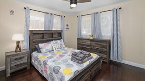 A bedroom with a bed, a nightstand, a dresser, a ceiling fan, and patterned curtains. - Cozy 2B/1Bth w Great Access to Airport (Fresno)