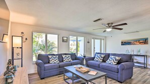 A modern living room with two grey sofas, a wooden coffee table, and a ceiling fan. - Englewood Escape w/ Screened-In Pool & Grill! (Englewood)