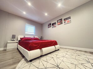 Une chambre à coucher avec un lit, des tables de chevet, une fenêtre et des œuvres d’art murales.